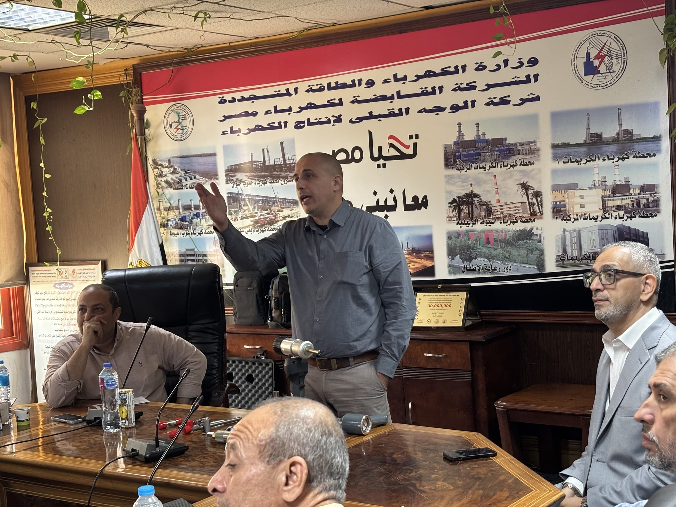 A speaker addressing the room beneath the Upper Egypt Electricity Production Co. banner